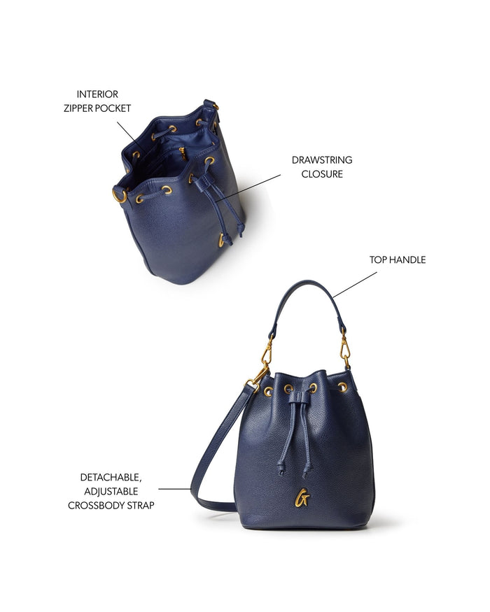 Navy medium pebble bucket bag featuring a drawstring closure, top handle, and detachable adjustable crossbody strap.