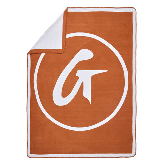 Brown classic throw blanket with a large white circular logo and stylized letter "G" in the center.