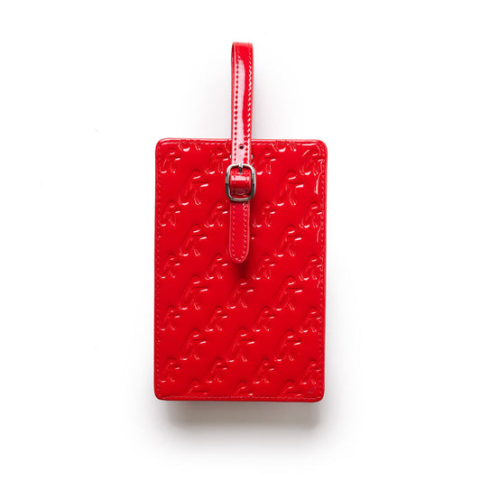 Red glossy monogram luggage tag with embossed logo pattern and adjustable strap with buckle.