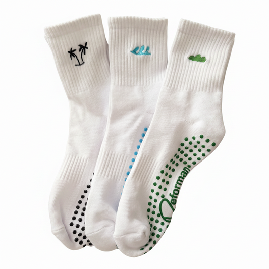 Three white socks with different designs and branding on a textured surface